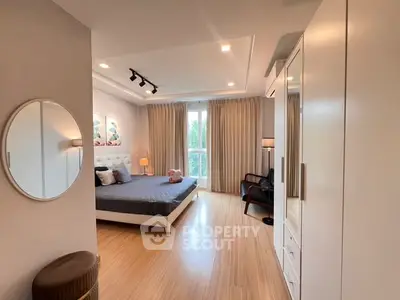 Spacious bedroom with modern decor and large window offering natural light.