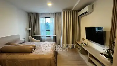 Modern bedroom with stylish decor, featuring a cozy bed, wall-mounted TV, and large window with curtains.