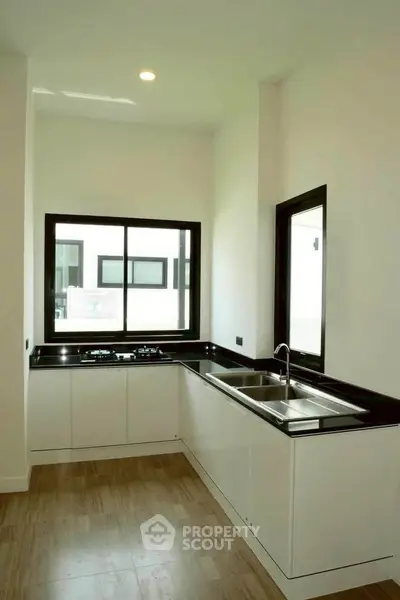Modern kitchen with sleek black countertops and large windows for natural light.