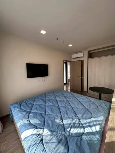 Modern bedroom with cozy blue bedding and wall-mounted TV in a stylish apartment.
