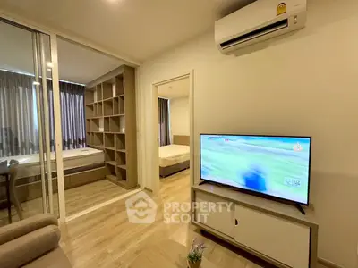 Modern apartment interior with open living room and bedroom, featuring sleek furniture and air conditioning.