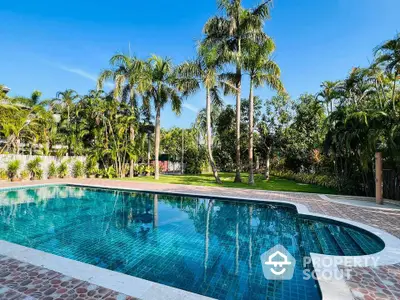 Luxurious tropical pool surrounded by lush greenery and palm trees, perfect for relaxation and leisure.