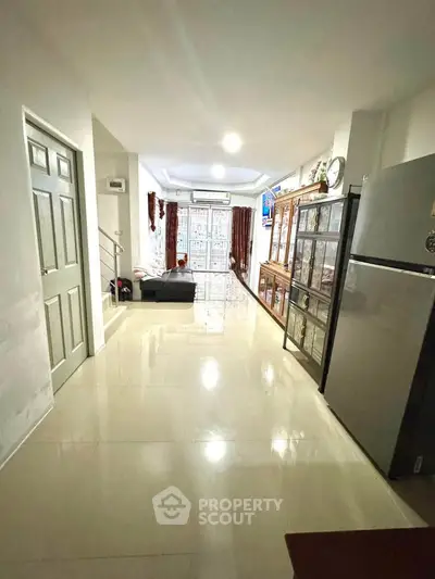 Spacious living area with modern furnishings and large fridge, perfect for family gatherings.