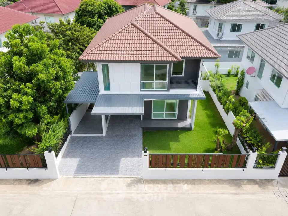 Charming two-story house with red-tiled roof, lush green lawn, and modern driveway in a serene neighborhood.