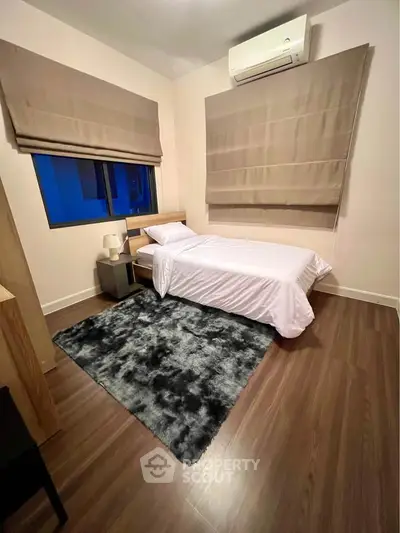 Cozy bedroom with modern decor and wooden flooring, featuring a single bed and stylish rug.