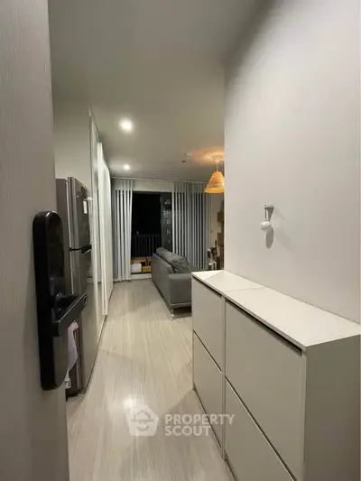 Modern apartment hallway leading to a cozy living room with balcony view.