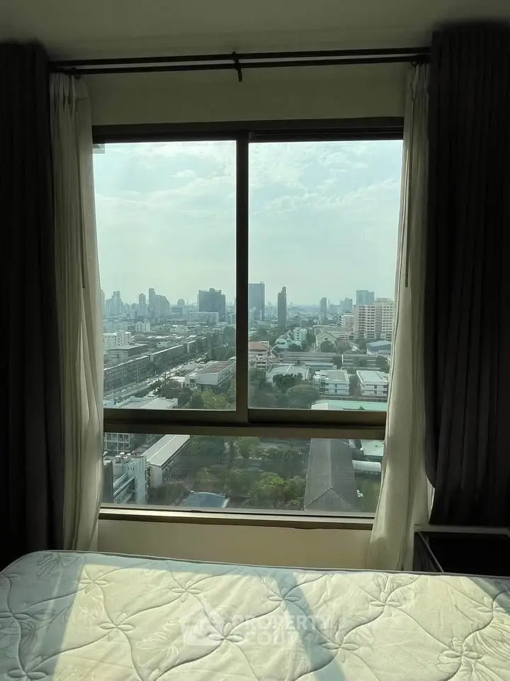 Spacious bedroom with stunning city view through large window, perfect for urban living.