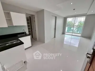 Modern open-layout kitchen and living area with balcony view in urban apartment.