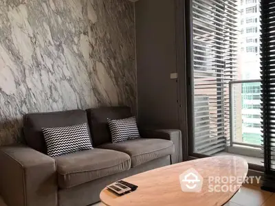 Elegant living room with marble walls, plush sofa, and modern oval coffee table, complemented by natural light filtering through stylish blinds.