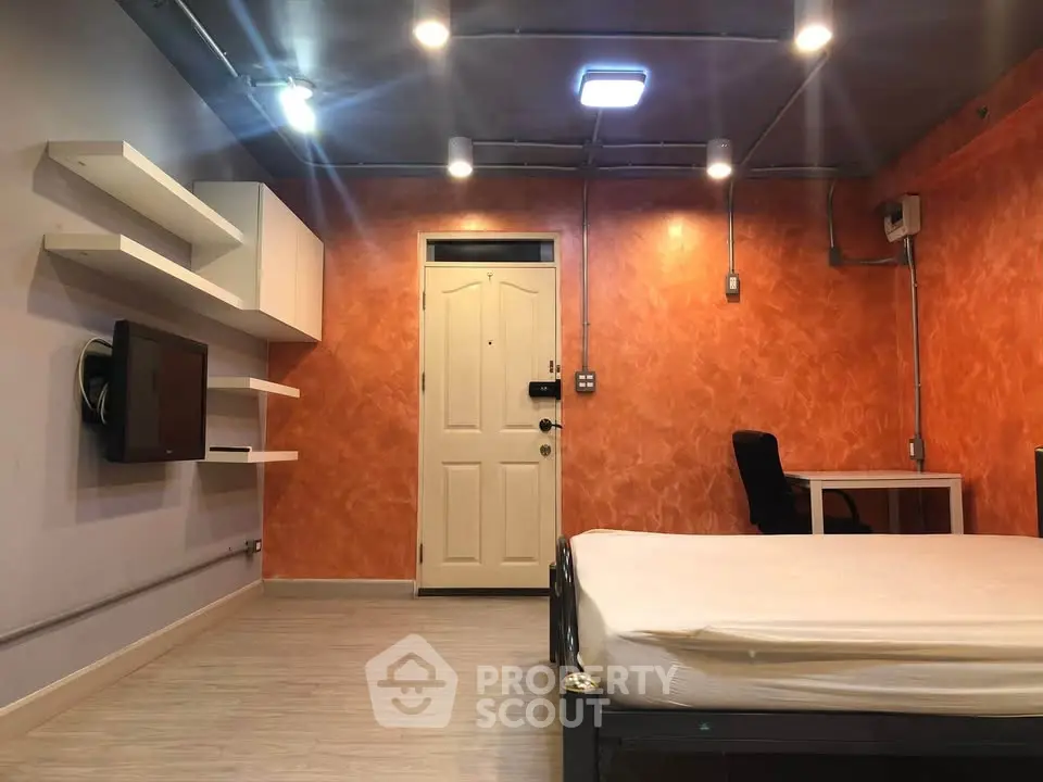 Modern bedroom with orange accent wall, sleek shelving, and minimalist decor.