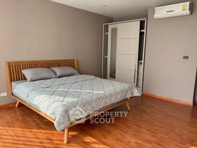 Spacious bedroom with wooden flooring and modern air conditioning unit