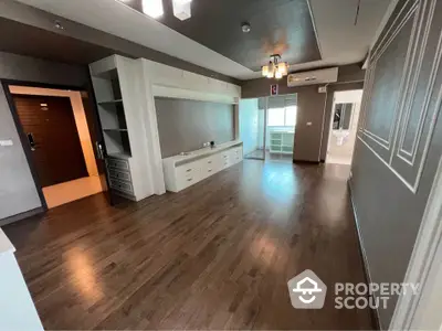 Spacious modern living room with hardwood floors and built-in storage in a stylish apartment.