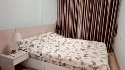 Cozy bedroom with elegant curtains and stylish bedding in modern apartment.