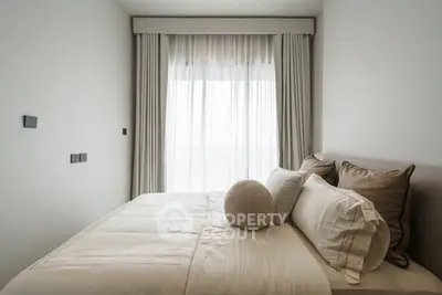 Cozy bedroom with elegant decor and natural light through large window.