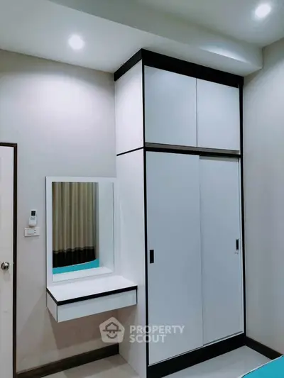Modern bedroom with sleek white wardrobe and built-in vanity mirror, perfect for stylish storage solutions.