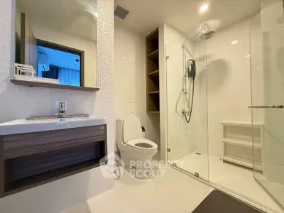 Modern bathroom with glass shower and sleek fixtures in contemporary apartment.