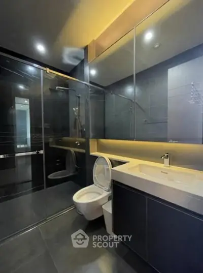 Modern bathroom with sleek black tiles and glass shower enclosure