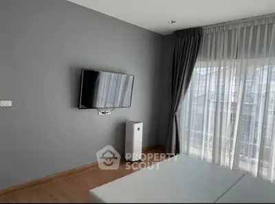 Modern living room with wall-mounted TV and floor-to-ceiling windows in a stylish apartment.