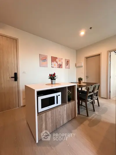 Modern kitchen with microwave and dining area, featuring stylish decor and wooden accents.
