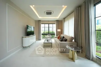 Modern living room with elegant decor and large windows offering natural light.