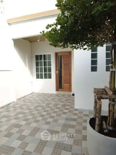 Charming entrance with modern wooden door and tiled patio, perfect for welcoming guests.