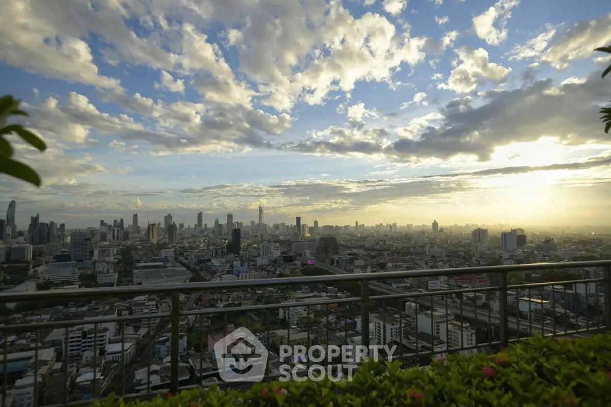 Stunning cityscape view from a high-rise balcony at sunset, showcasing urban skyline and vibrant sky.
