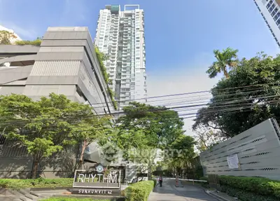 Modern high-rise building with lush greenery at Rhythm Sukhumvit 42 entrance.