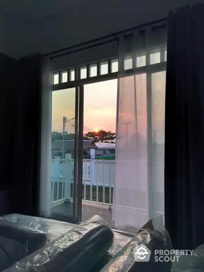 Serene bedroom with a stunning sunset view through large glass doors leading to a spacious balcony, perfect for unwinding.