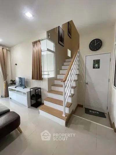 Modern living room with stylish staircase and wall clock, perfect for contemporary homes.