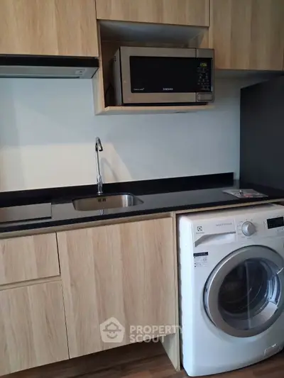 Modern kitchen with wooden cabinets, built-in microwave, and washing machine