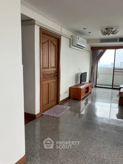 Spacious living room with balcony and city view, featuring modern decor and natural light.