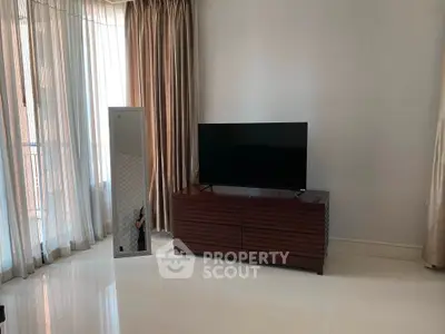 Spacious living room with modern TV stand and floor-to-ceiling curtains