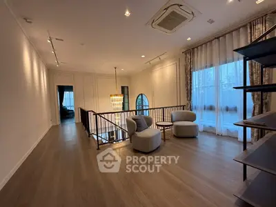 Elegant living area with modern seating and large windows, featuring stylish lighting and wooden flooring.