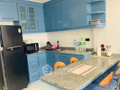 Modern kitchen with blue cabinets, granite countertops, and dining area in a stylish apartment.