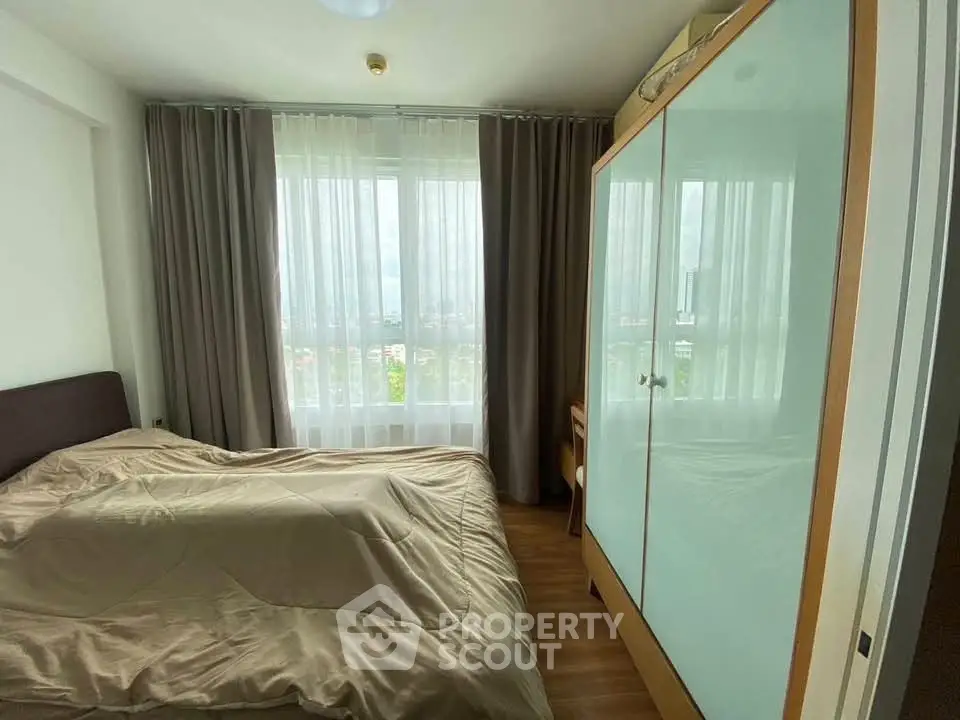 Cozy bedroom with large window and modern wardrobe in a bright apartment.