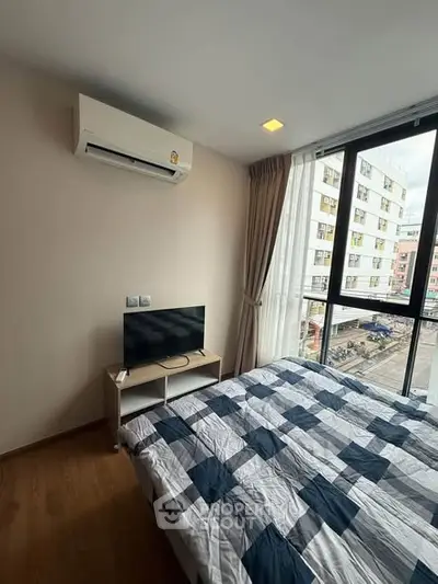 Modern bedroom with large window and air conditioning in urban apartment