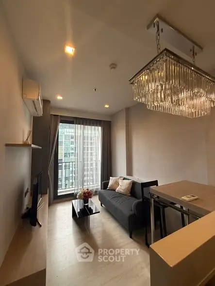 Modern living room with elegant chandelier and city view balcony in a stylish apartment.