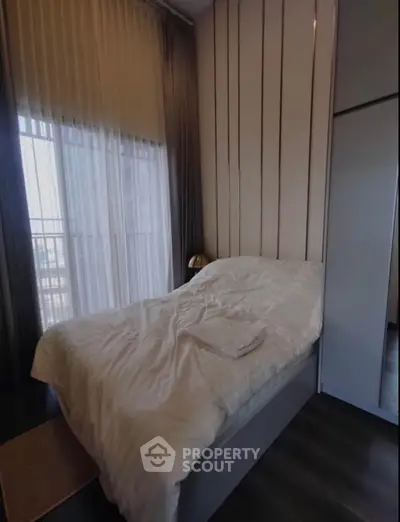 Cozy bedroom with large window and modern decor, perfect for relaxation and comfort.