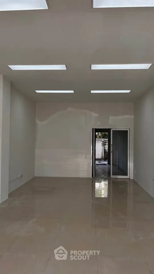 Spacious empty room with glossy tiled floor and modern lighting, ideal for customization.