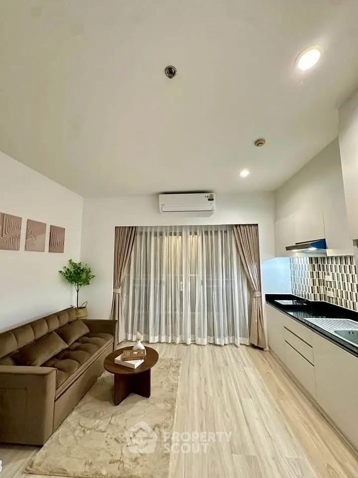 Modern living room with sleek kitchen, featuring a cozy sofa and elegant decor.