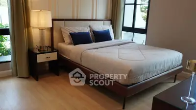 Elegant bedroom with modern decor and large windows offering natural light.