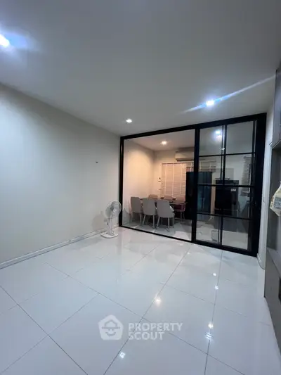 Spacious modern living room with glass partition and elegant dining area.