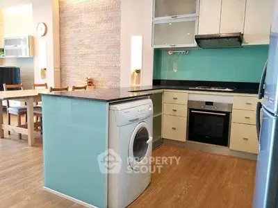 Modern kitchen with washing machine and dining area, featuring sleek design and open layout.