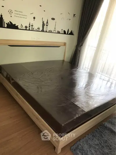 Modern bedroom with wooden bed frame and large window, featuring stylish wall art and cozy rug.