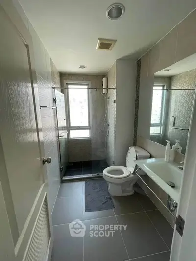 Modern bathroom with sleek design, featuring a glass shower enclosure and contemporary fixtures.