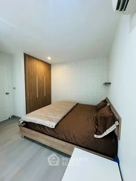 Modern bedroom with stylish wooden wardrobe and cozy bedding in a contemporary apartment.