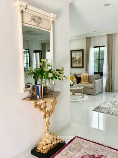 Elegant living room with luxurious decor and golden accents, featuring a stylish mirror and plush seating area.