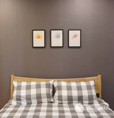 Cozy bedroom with stylish checkered bedding and a trio of floral wall art above a wooden headboard, creating a serene sleeping space.