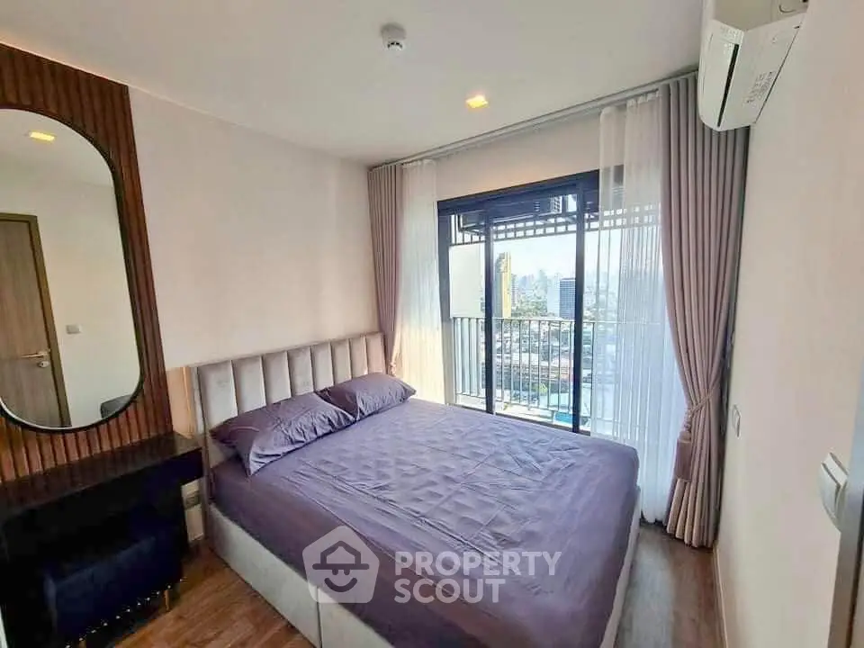 Modern bedroom with large window and city view, featuring elegant decor and natural light.