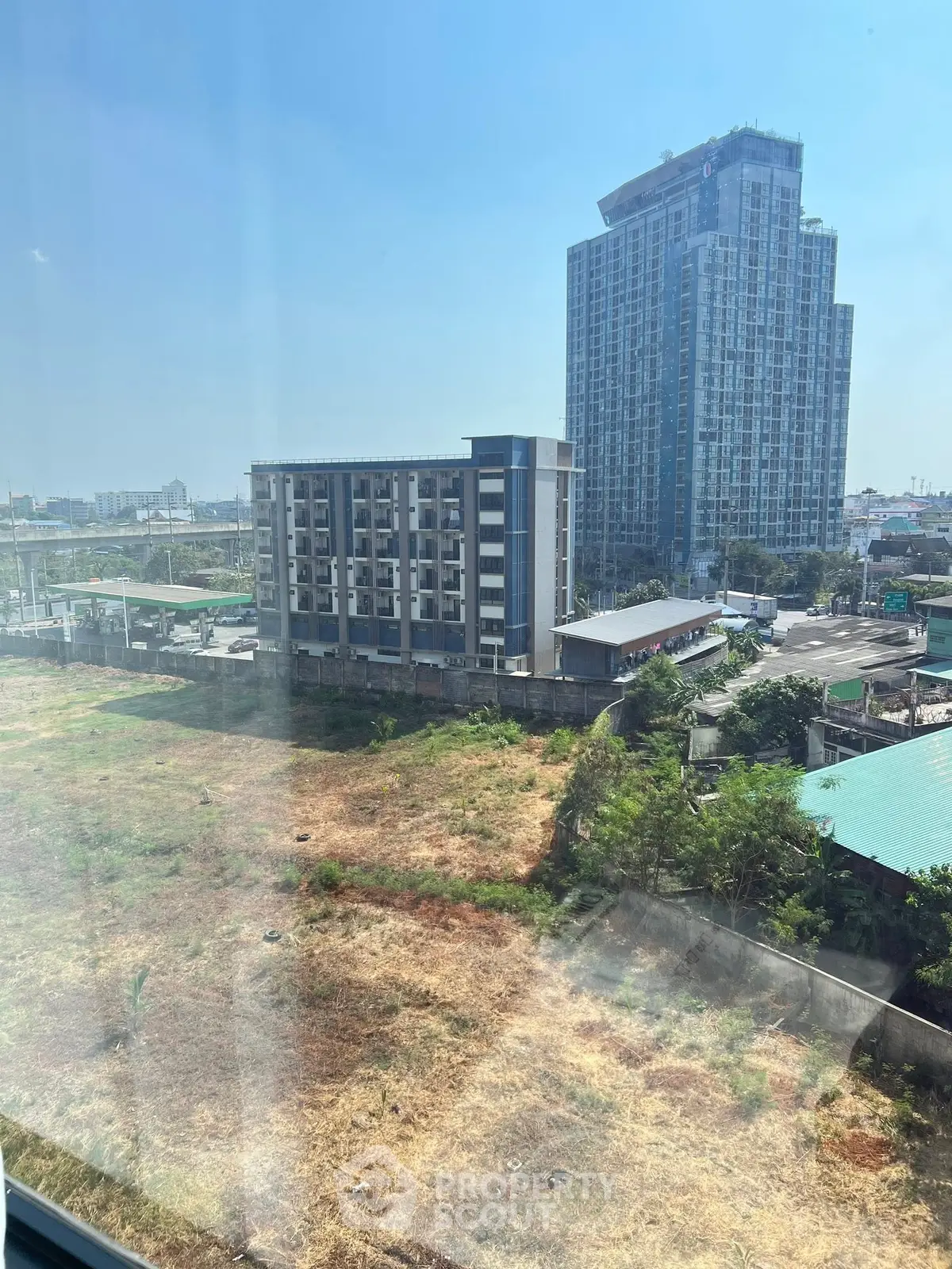 Stunning cityscape view from high-rise building window, showcasing urban development and open land.